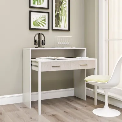 A desk with drawers and a shelf, placed in a room with artwork on the wall and a chair nearby.