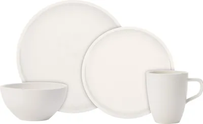 A set of white ceramic dishes including a large plate, a smaller plate, a bowl, and a mug, arranged on a white background.