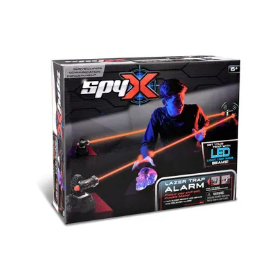 The image shows the packaging of a SpyX Lazer Trap Alarm toy, with a boy demonstrating its use with laser beams.