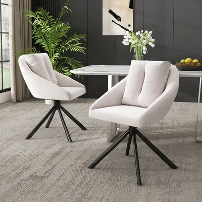 Two beige upholstered chairs with black metal legs are placed in a dining room setting.