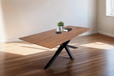 A wooden dining table with a black metal base is shown in a room with wooden floors and white walls.