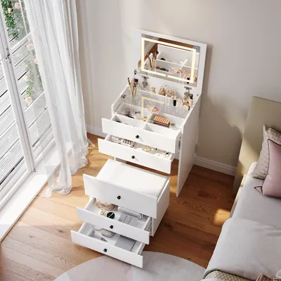 A white vanity table with a lighted mirror and drawers, placed next to a bed in a bedroom.