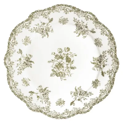 A white plate with a green floral pattern and a scalloped edge.