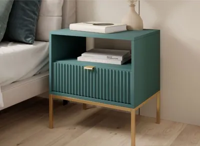 A teal nightstand with gold legs is placed next to a bed.