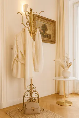 A hallway with a coat rack, painting, and side table.