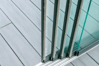 A close-up view of a sliding glass door track with weather stripping and a wooden deck.