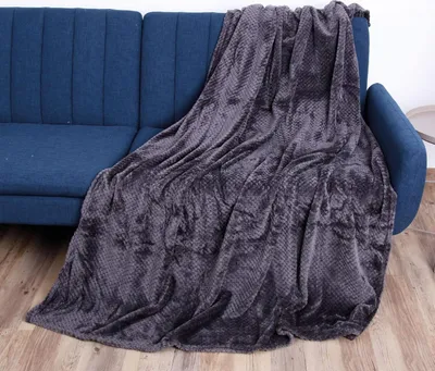 A dark gray textured blanket is draped over a blue sofa.