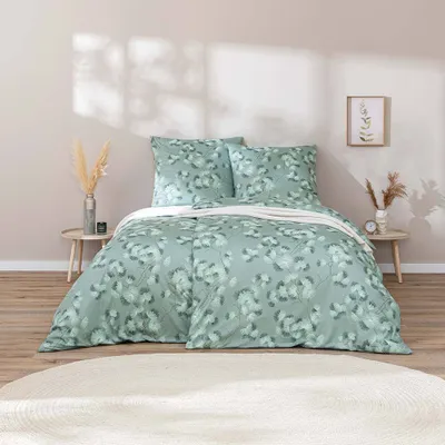 A neatly made bed with a floral pattern duvet cover and pillows, set in a bedroom with decorative elements.