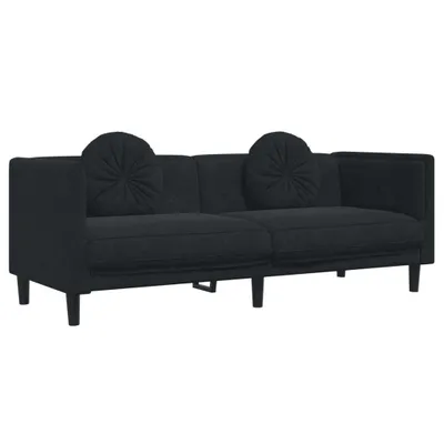 A black sofa with two round throw pillows sits against a white background.