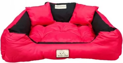 A red and black dog bed with two small pillows.