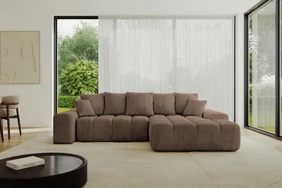 A modern living room with a large sectional sofa in front of a window with sheer curtains.