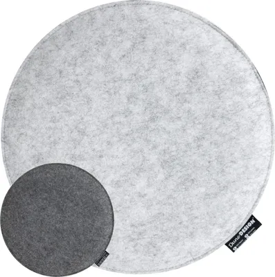 A round, light gray felt seat cushion is shown from a top-down perspective. A smaller, dark gray felt seat cushion is placed on top of the larger one, towards the bottom left. A black label with white text is visible on the edge of the larger cushion.
