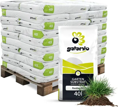 A pallet of bagged garden substrate with a single bag in the foreground and a pile of substrate with grass.