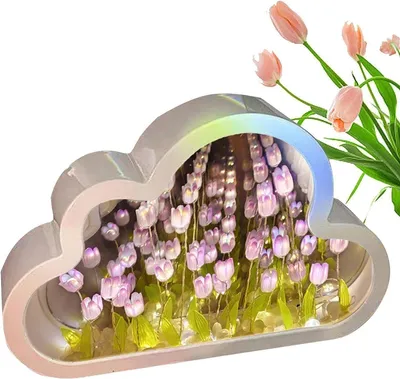 A cloud-shaped night light with artificial tulips inside, with real tulips in the background.