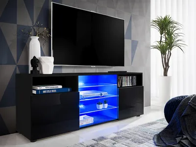 A modern black TV stand with blue LED lighting, displaying electronic devices and decorative items.