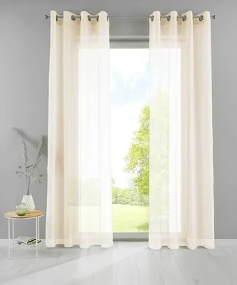 A window with cream-colored curtains and a small side table with a vase and books.