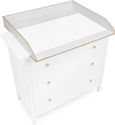 A white changing table topper is placed on top of a white dresser.