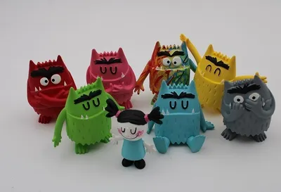 A collection of colorful monster figurines and a small human figurine arranged on a white background.