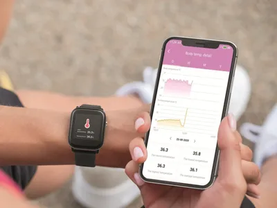 A person is holding a smartphone and wearing a smartwatch, both displaying health data.