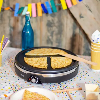 A crepe maker with crepes and party decorations.