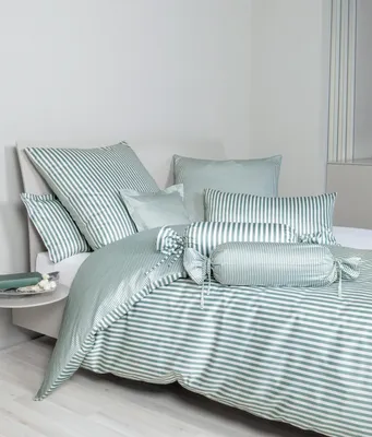 A neatly made bed with striped bedding and several pillows.