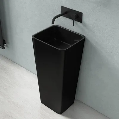 A modern black freestanding sink with a wall-mounted faucet in a bathroom.