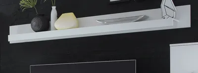A white shelf mounted on a black textured wall, displaying decorative items.