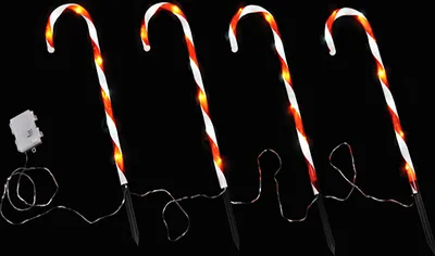 Four illuminated candy cane garden stakes against a black background.