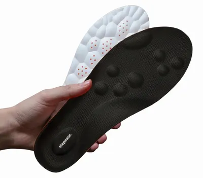 Eine Hand, die zwei Stepease-Einlegesohlen hält, eine schwarz mit strukturierter Oberfläche und Fußgewölbestütze, die andere weiß mit Wabenmuster und roten Belüftungslöchern