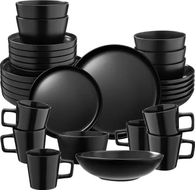 A collection of black ceramic dinnerware, including plates, bowls, and mugs, neatly arranged.