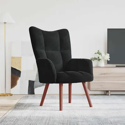 A black velvet armchair is placed on a rug in a living room setting, with a floor lamp and abstract art in the background.