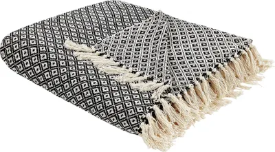 A folded black and white patterned throw blanket with cream-colored fringe is displayed on a white background.