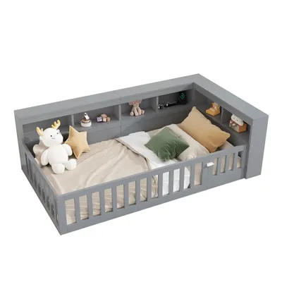 A grey daybed with built-in shelving and a slatted side rail, shown with stuffed toys and pillows on a white background.