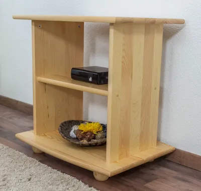A light wood TV stand with two shelves, placed against a white wall and on a wooden floor with a rug.
