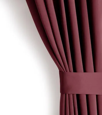 A close-up of a burgundy curtain, tied back with a matching fabric band.