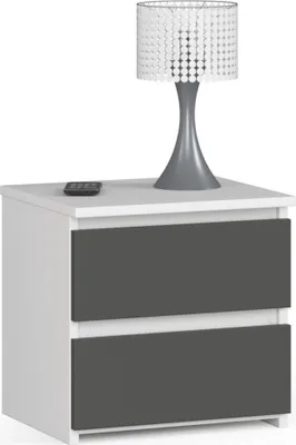 A white nightstand with two graphite gray drawers, topped with a decorative lamp and a remote control.