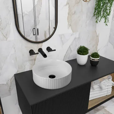 A modern bathroom vanity with a white vessel sink and black fixtures.