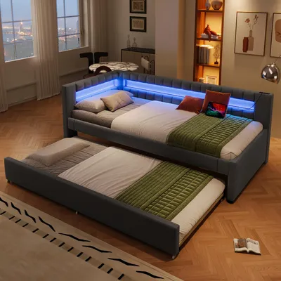 A bedroom or living room setting with a daybed and a pull-out trundle bed, illuminated by blue LED lights.