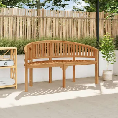 A wooden bench sits on a patio in front of a bamboo fence.