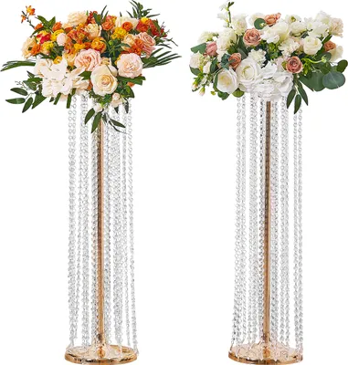Two tall, gold-colored flower stands adorned with crystal beads and topped with floral arrangements.