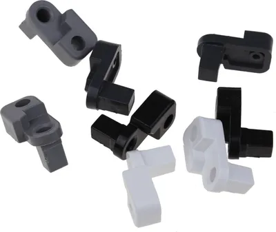 A collection of small plastic L-shaped connectors in gray, black, and white, scattered against a white background.