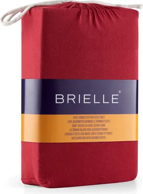 A folded red fitted sheet packaged in its own fabric bag, with a branded label wrapped around it.