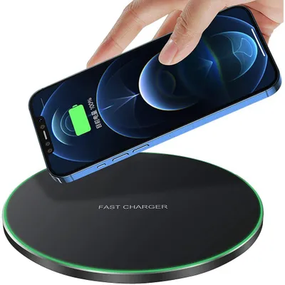 A hand is placing a smartphone onto a wireless charging pad.