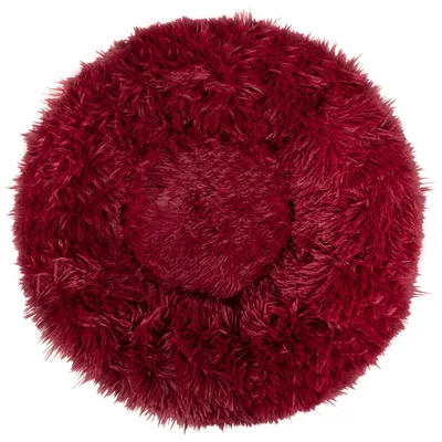 A top-down view of a round, fluffy dog bed in a deep red color.