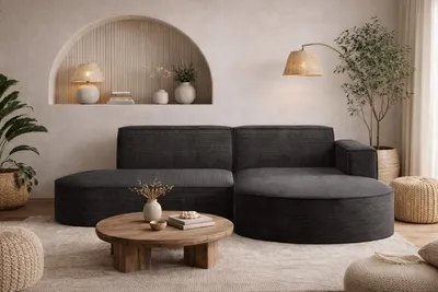 A modern living room with a dark gray sectional sofa, a round wooden coffee table, and decorative elements.