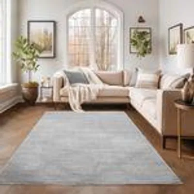 A living room with a sectional sofa, a large arched window, and a light gray rug in the foreground.