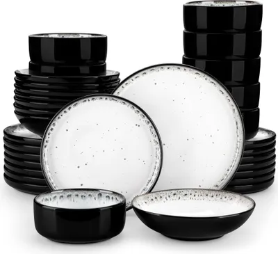 A collection of black and white speckled ceramic plates and bowls stacked and arranged on a white background.