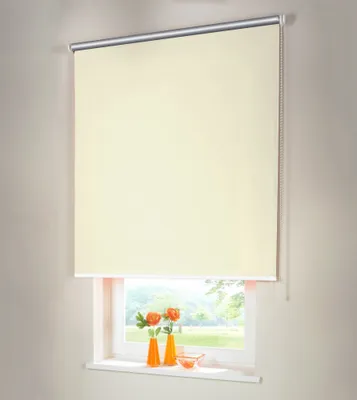 A cream-colored roller blind is shown covering most of a window, with a glimpse of an outdoor scene and two small orange vases with flowers on the windowsill below.