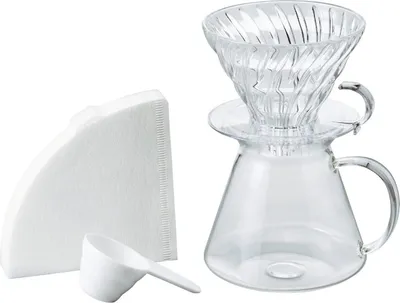 A coffee brewing kit including a glass carafe, a glass dripper, paper filters, and a scoop, arranged on a white background.