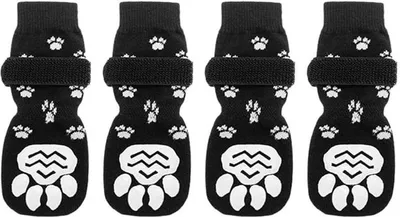 Four black dog socks with white paw print patterns and white paw-shaped grips on the bottom, arranged in a row.